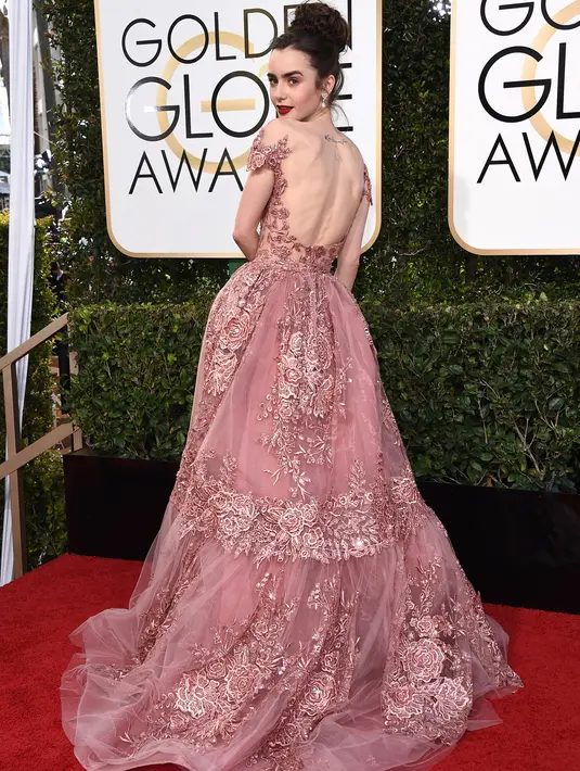 Penampilan aktris Lily Collins di karpet merah ajang Golden Globe Awards di California, Minggu (8/1). Lily Collins memamerkan detail bagian belakang gaunnya yang mengekspos tato milik sang aktris 27 tahun itu. (Jordan Strauss/Invision/AP)