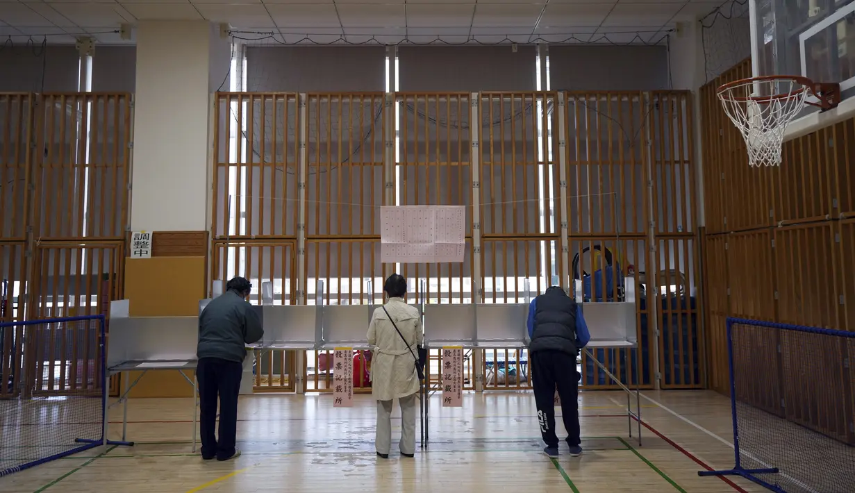 Para pemilih bersiap untuk memberikan suara mereka dalam pemilihan majelis rendah saat perwakilan dari komisi administrasi pemilihan lokal mengamati di sebuah TPS, Tokyo, Jepang, Minggu (31/10/2021). Jepang menggelar Pemilu di tengah pandemi COVID-19. (AP Photo/Eugene Hoshiko)