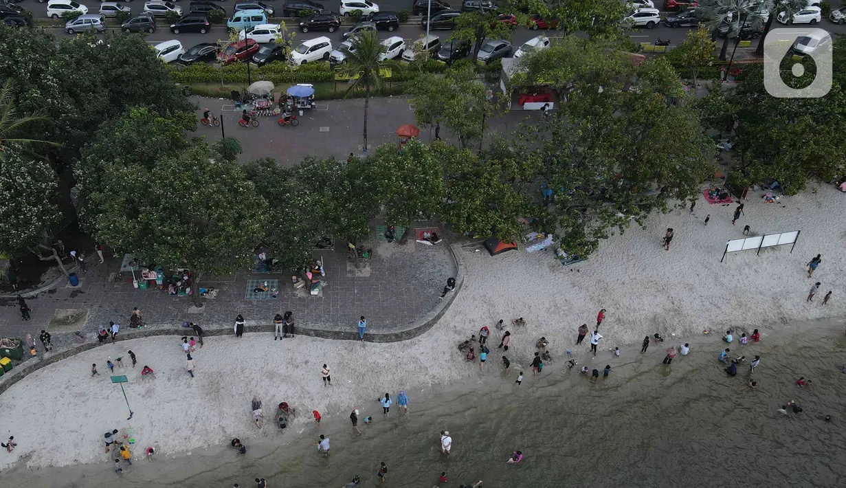 Pemandangan udara warga berlibur di Pantai Ancol, Pademangan, Jakarta Utara, Rabu (1/6/2022). Libur Nasional Hari Lahir Pancasila, dimanfaatkan warga mengajak sanak saudara tamasya di Pantai Ancol. (Liputan6.com/Herman Zakharia)