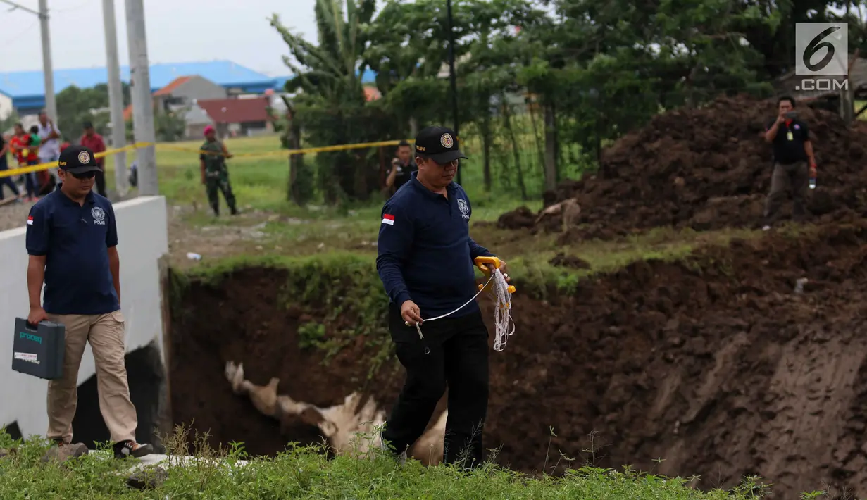 Petugas Puslabpor Bareskrim Polri membawa alat ukur saat olah TKP longsornya Underpass Perimeter Selatan, Bandara Soekarno Hatta (Soetta), Tangerang, Banten, Selasa (6/2). Satu orang tewas dalam kejadian tersebut. (Liputan6.com/Angga Yuniar)