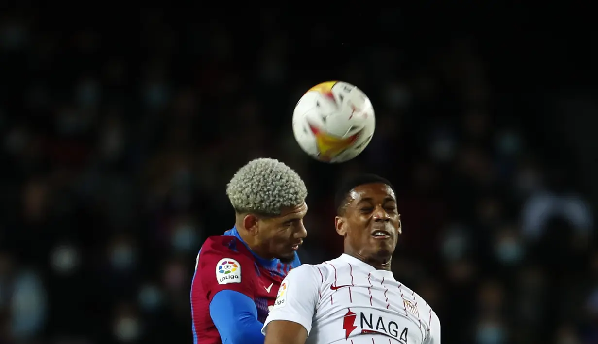 Bek Barcelona, Ronald Araujo berebut bola dengan penyerang Sevilla, Anthony Martial pada pertandingan lanjutan La Liga Spanyol di stadion Camp Nou di Barcelona, Spanyol, Senin (4/4/2022). Tambahan tiga angka ini lantas membawa Barcelona naik dua peringkat sekaligus. (AP Photo/Joan Monfort)