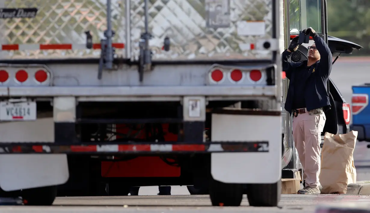 Polisi mengumpulkan bukti di lokasi terparkirnya truk yang berisi sembilan mayat di luar sebuah supermarket, Texas, Minggu (23/7).  Menurut laporan, orang-orang di truk itu berada dalam kondisi dehidrasi serta terkena sengatan panas. (AP Photo/Eric Gay)