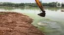 Petugas menggunakan alat berat untuk mengeruk lumpur di kawasan Setu Babakan, Jakarta, Rabu (21/10/2020). Program pengerukan lumpur kali, sungai, atau waduk di Jakarta bertujuan untuk mencegah banjir serta mengantisipasi adanya genangan air saat musim penghujan. (Liputan6.com/Immanuel Antonius)