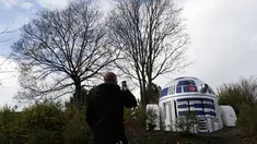 Seorang pria memotret ventilasi bunker nuklir yang dicat oleh ulah kreatif seniman jalanan sehingga menyerupai robot R2-D2 di film Star Wars di sebuah taman di Praha, Republik Ceko, (28/10). (AP Photo/Petr David Josek)