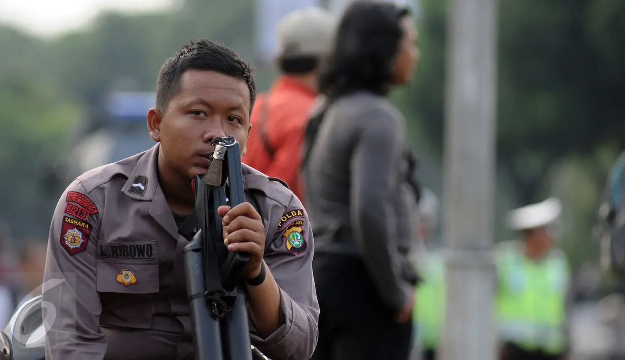 Polisi beristirahat sambil memegang senjata di depan Istana Negara, Jakarta, Jumat (4/11). Ribuan aparat gabungan disiagakan saat massa melakukan aksi menuntut penegakan hukum kasus dugaan penistaan agama. (Liputan6.com/Helmi Fithriansyah)