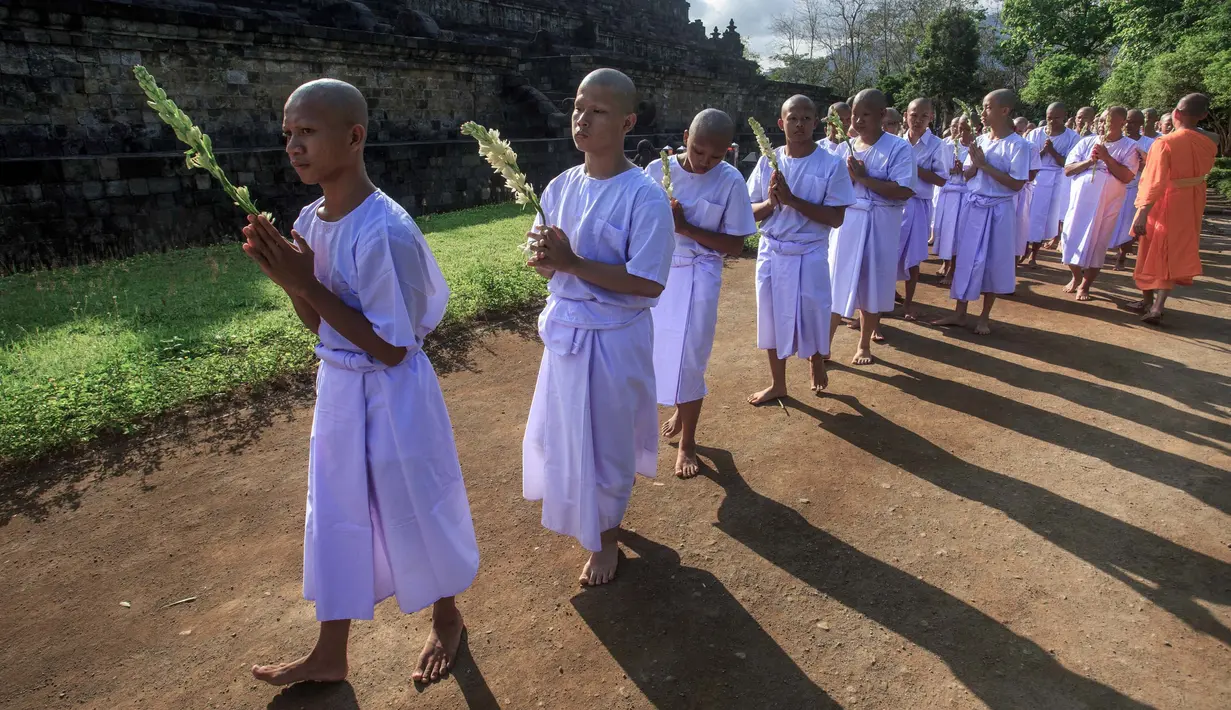 Seorang biksu Buddha (kanan) menyaksikan para calon biksu bermeditasi sambil berjalan tanpa alas kaki dalam ritual tahunan 'Pabbaja Samanera', di kawasan Candi Borobudur, Magelang, Jawa Tengah, 19 Desember 2023. (DEVI RAHMAN/AFP)