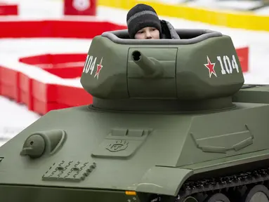 Seorang anak laki-laki mengendarai model tank T-34 era Soviet yang legendaris di objek wisata petualangan anak-anak Tankodrom di taman Sokolniki di Moskow, Rusia (6/1/2020). Model tank ini memiliki mesin pembakaran internal dan kontrol seperti aslinya. (AP Photo/Alexander Zemlianichenko)