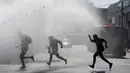 Sejumlah pelajar berlari saat petugas menembakkan jet air di Santiago , Chile , 21 April 2016. Para Demonstran menuntut perubahan sistem pendidikan di Chile. (REUTERS / Clemente Villavicencio)