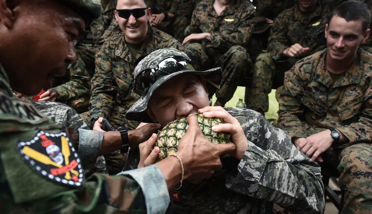 Sersan Mayor Marinir Thailand Chaiwat Ladsin, memegang nanas yang digigit oleh anggota marinir Korea Selatan saat latihan gabungan Cobra Gold antara militer AS dan Thailand di Chonburi, Thailand (19/2). (AFP Photo/Lilian Suwanrumpha)