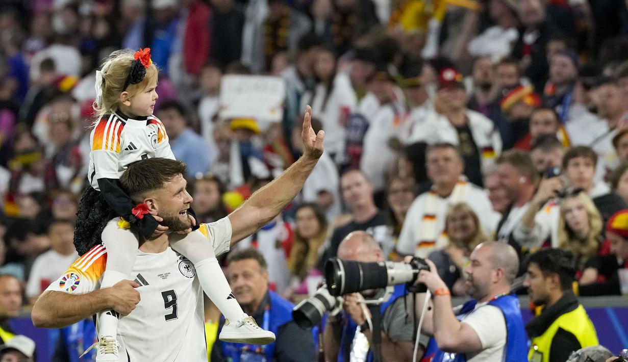 Pemain Jerman, Niclas Fullkrug merayakan kemenangan atas Skotlandia bersama putrinya setelah laga pembuka Grup A Euro 2024 di Allianz Arena, Munchen, Jerman, Sabtu (15/06/2024) WIB. (AP Photo/Frank Augstein)