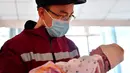 Hao Tiedan, seorang petugas medis, menggendong putrinya yang baru lahir di Taiyuan, Provinsi Shanxi, China utara, pada 4 Februari 2020, sebelum bertolak menuju Provinsi Hubei, China tengah, untuk bergabung dalam upaya memerangi coronavirus baru. (Xinhua/Cao Yang)