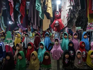 Seorang perempuan melintas di depan penjual gamis dan baju anak di pasar Parung, Bogor, Jawa Barat, Kamis (18/2/2021). Dampak pandemi COVID-19 yang berkepanjangan pedagang mengaku omset penjualan gamis dan baju anak turun 85 persen semenjak awal tahun lalu hingga sekarang. (Liputan6.com/Johan Tallo)