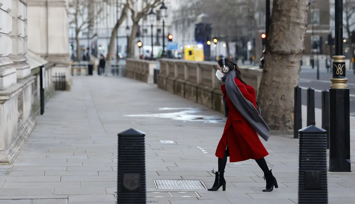 Seorang pejalan kaki yang mengenakan masker untuk mengurangi penyebaran Covid-19, berjalan di sepanjang Whitehall di pusat kota London (5/1/2022). Kasus Covid-19 harian negara itu menembus 200.000 untuk pertama kalinya. (AFP/Tolga Akmen)