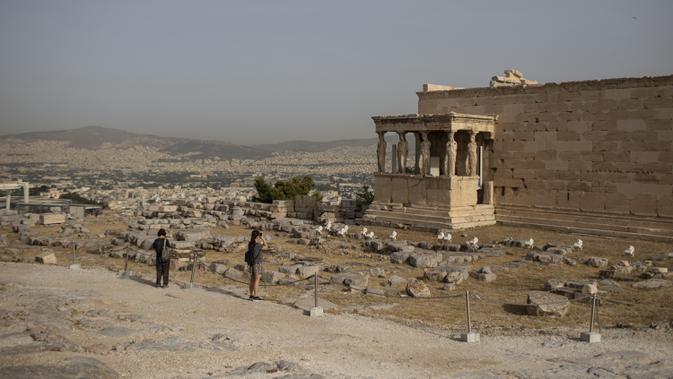 Pengunjung mengambil gambar Patung Caryatid di Kuil Erechtheion, Bukit Acropolis, Athena, Yunani, Senin (18/5/2020). Yunani kembali membuka kota kuno Acropolis serta situs-situs lainnya setelah dua bulan ditutup selama lockdown akibat pandemi virus corona COVID-19. (AP Photo/Petros Giannakouris)