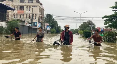 Penduduk setempat menyeberangi jalan yang banjir di Bago, sekitar 80 kilometer (50 mil) timur laut Yangon, Myanmar, Senin (9/10/2023). Banjir yang dipicu oleh hujan lebat di wilayah selatan Myanmar telah menyebabkan lebih dari 10.000 orang mengungsi dan mengganggu lalu lintas di jalur kereta api yang menghubungkan kota-kota terbesar di negara itu, kata para pejabat dan media pemerintah pada hari Senin. (AP Photo/Thein Zaw)