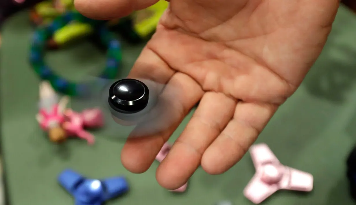 Pemilik toko mempraktekan cara bermain fidget spinner di toko Funky Monkey Toys di Oxford, Mich (11/5). Dalam bahasa Indonesia ‘fidget’ berarti gelisah atau cemas, sedangkan 'spinner' berarti pemutar. (AP Photo / Carlos Osorio)