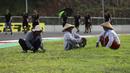 Namun dibalik semua itu ada beberapa visual yang menari untu disimak. Salah satunya  kebahagian warga lokal yang sedang merapihkan rumput di area Sirkuit Internasional Mandalika agar terlihat lebih indah dan asri. (AP Photo/Achmad Ibrahim)