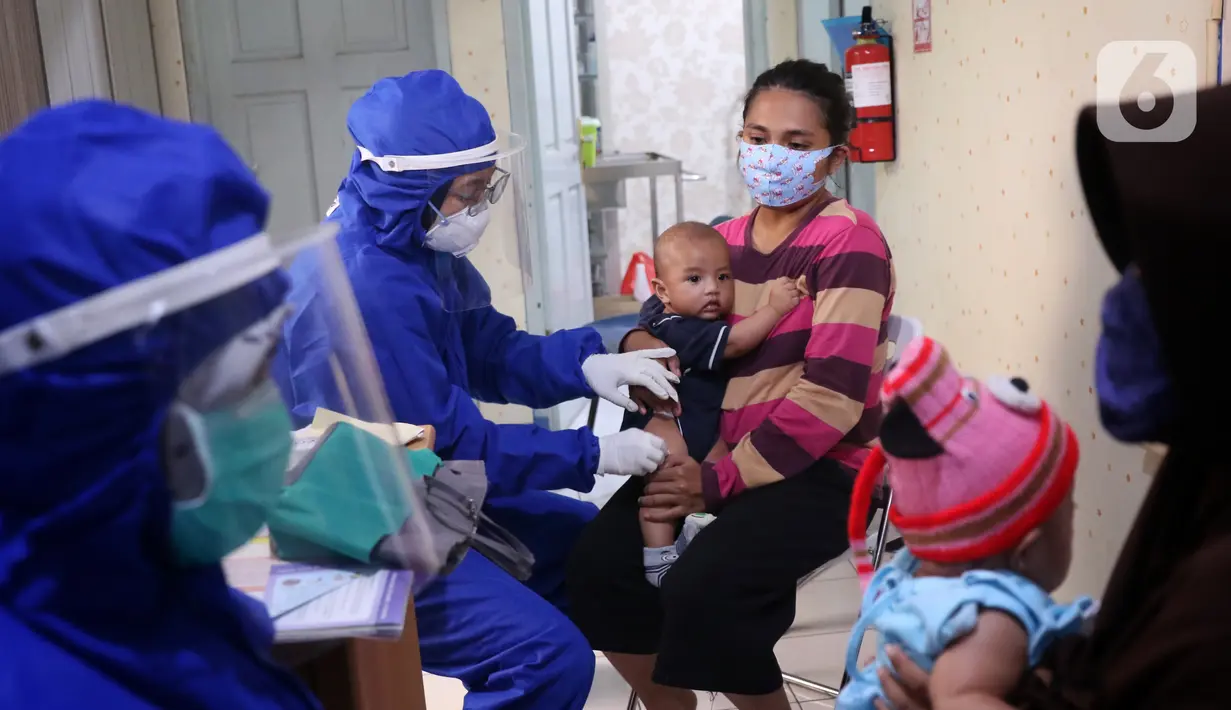 Bidan mengenakan alat pelindung diri (APD) saat melakukan imunisasi kepada bayi di Puskesmas Karawaci Baru, Tangerang, Banten, Rabu (13/5/2020). Pelayanan imunisai sesuai jadwal ini diberikan kepada bayi untuk menambah kekebalan imun tubuh. (Liputan6.com/Angga Yuniar)