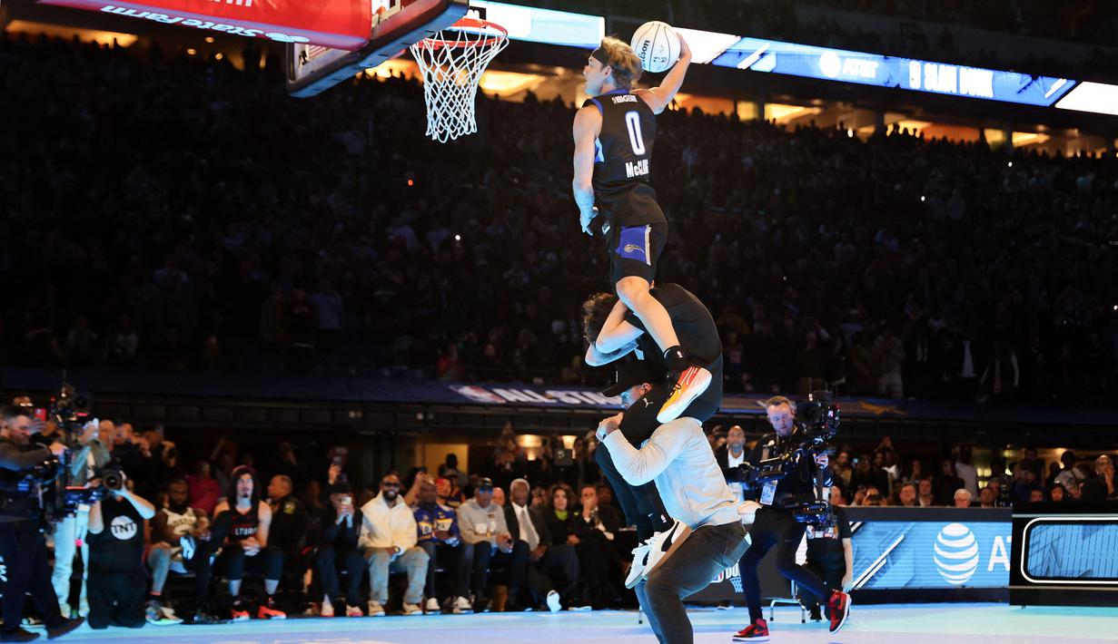 Pemain Osceola Magic, Mac McClung melakukan slam dunk dengan melompati dua orang saat kontes Slam Dunk di NBA All Star 2024 di Lucas Oil Stadium, Indianapolis, Amerika Serikat, Minggu (18/02/2024). (AFP/Getty Images/Stacy Revere)