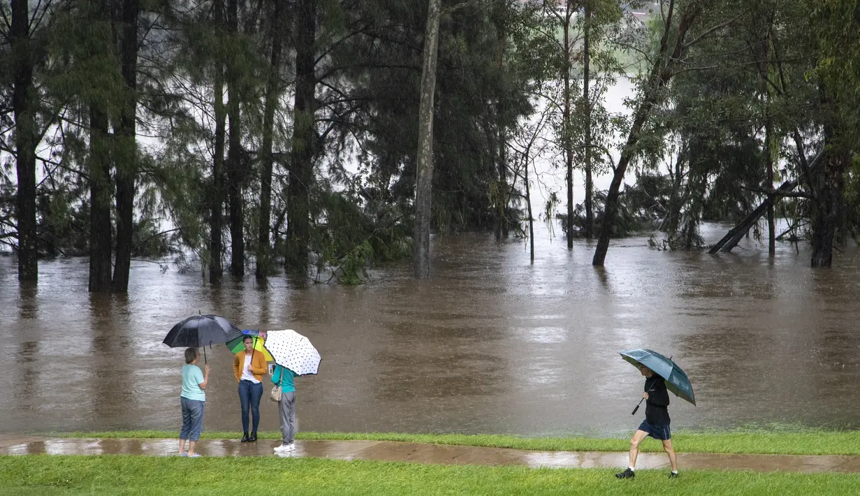 Orang-orang berdiri di tepi Sungai Nepean di Jamisontown di pinggiran barat Sydney (22/3/2021).  Negara bagian New South Wales yang padat penduduknya telah mengeluarkan lebih banyak perintah evakuasi menyusul banjir terburuk dalam beberapa dekade. (AP Photo/Mark Baker)