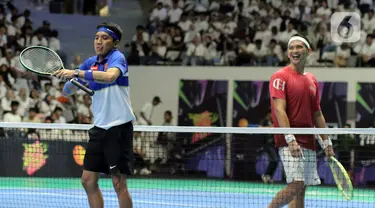 Desta (kiri) bereaksi saat melawan Rezky Aditya pada pertandingan tenis lantai Sport Party - Clash of Celebrity di Istora Senayan, Jakarta, Sabtu (23/12/2023). Desta berhasil mengalahkan Rezky dengan skor akhir 6-3. (Liputan6.com/Angga Yuniar)