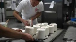 Pemilik toko roti Tim Kortuem menyiapkan kue berbentuk tisu toilet di toko roti Schuerener Backparadies di Dortmund, Jerman, 26 Maret 2020. Kelangkaan kertas tisu toilet memunculkan ide bagi pemilik toko roti itu membuat kue menyerupai barang yang diburu warga di tengah Covid-19 (Ina FASSBENDER/AFP)