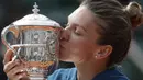 Simona Halep mencium trofi Prancis Terbuka 2018 setelah mengalahkan petenis Amerika, Sloane Stephens di Roland Garros stadium, Paris, Prancis, (9/6/2018). Simona menang 3-6, 6-4, 6-1. (AP/Alessandra Tarantino)