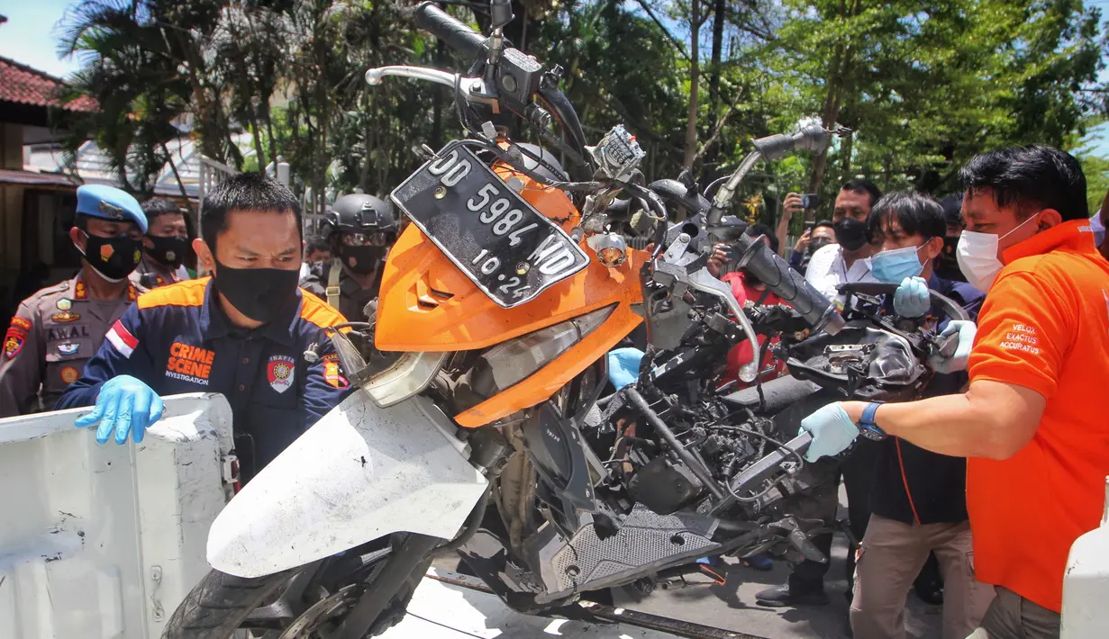 Polisi memindahkan sepeda motor yang digunakan dalam aksi bom bunuh diri saat rekonstruksi di Gereja Katedral Makassar, Sulawesi Selatan, Senin (29/3/2021). Teror bom yang terjadi pada Minggu (28/3) di pintu masuk halaman gereja tersebut melukai sejumlah orang. (INDRA ABRIYANTO/AFP)
