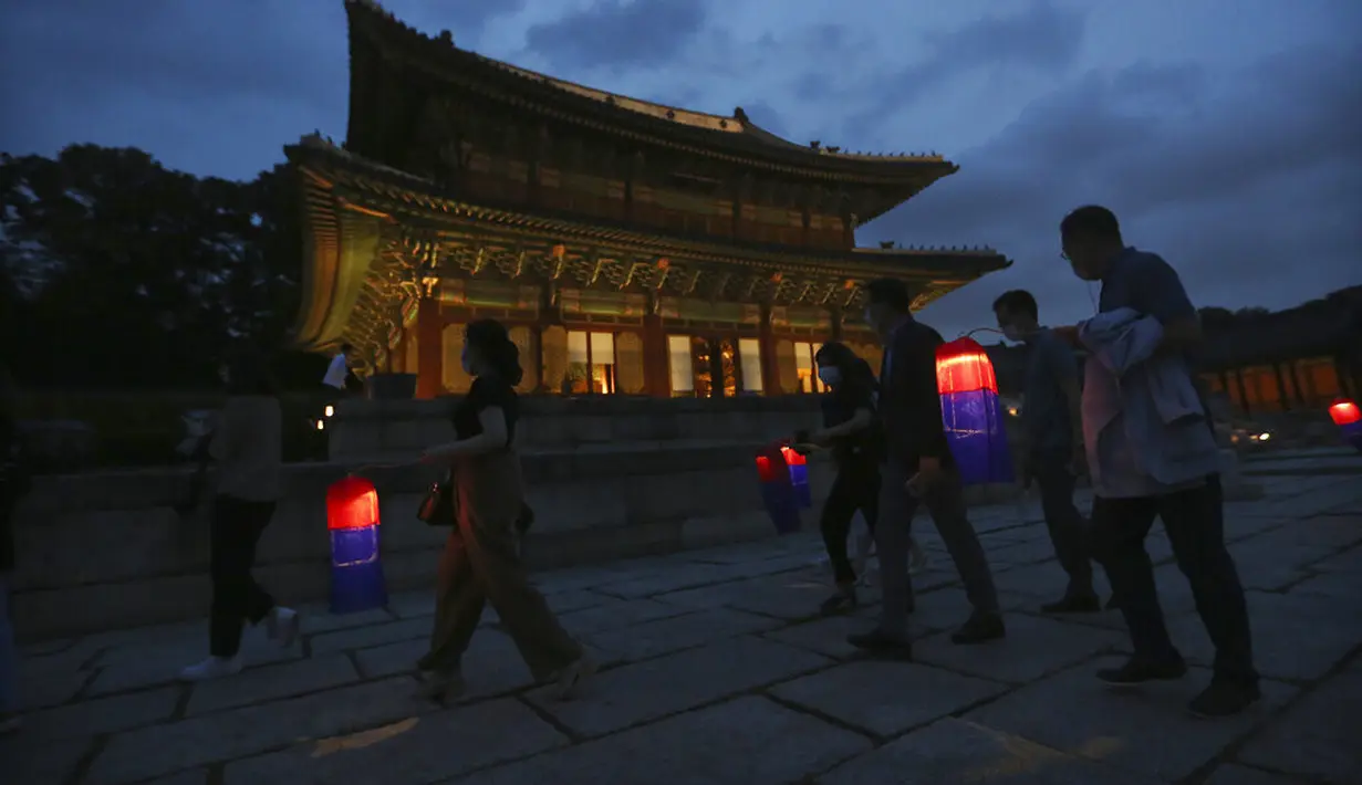 Pengunjung memegang lentera tradisional Korea berjalan-jalan selama Tur Cahaya Bulan di Istana Changdeokgung di Seoul, Korea Selatan, Kamis, (13/8/2020). Istana dibuka kembali pada Kamis setelah ditutup selama dua bulan karena pandemi Covid-19. (AP Photo/Ahn Young-joon)