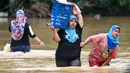 Warga membawa barang-barang mereka melalui air banjir di Kuala Kaung, dekat Lanchang di negara bagian Pahang Malaysia (4/1/2021).  Tiga sungai di negara bagian itu - Sungai Lepar, Sungai Lipis dan Sungai Lembing - telah melewati tingkat bahaya mereka pada hari Minggu. (AFP/Mohd Rasfan)