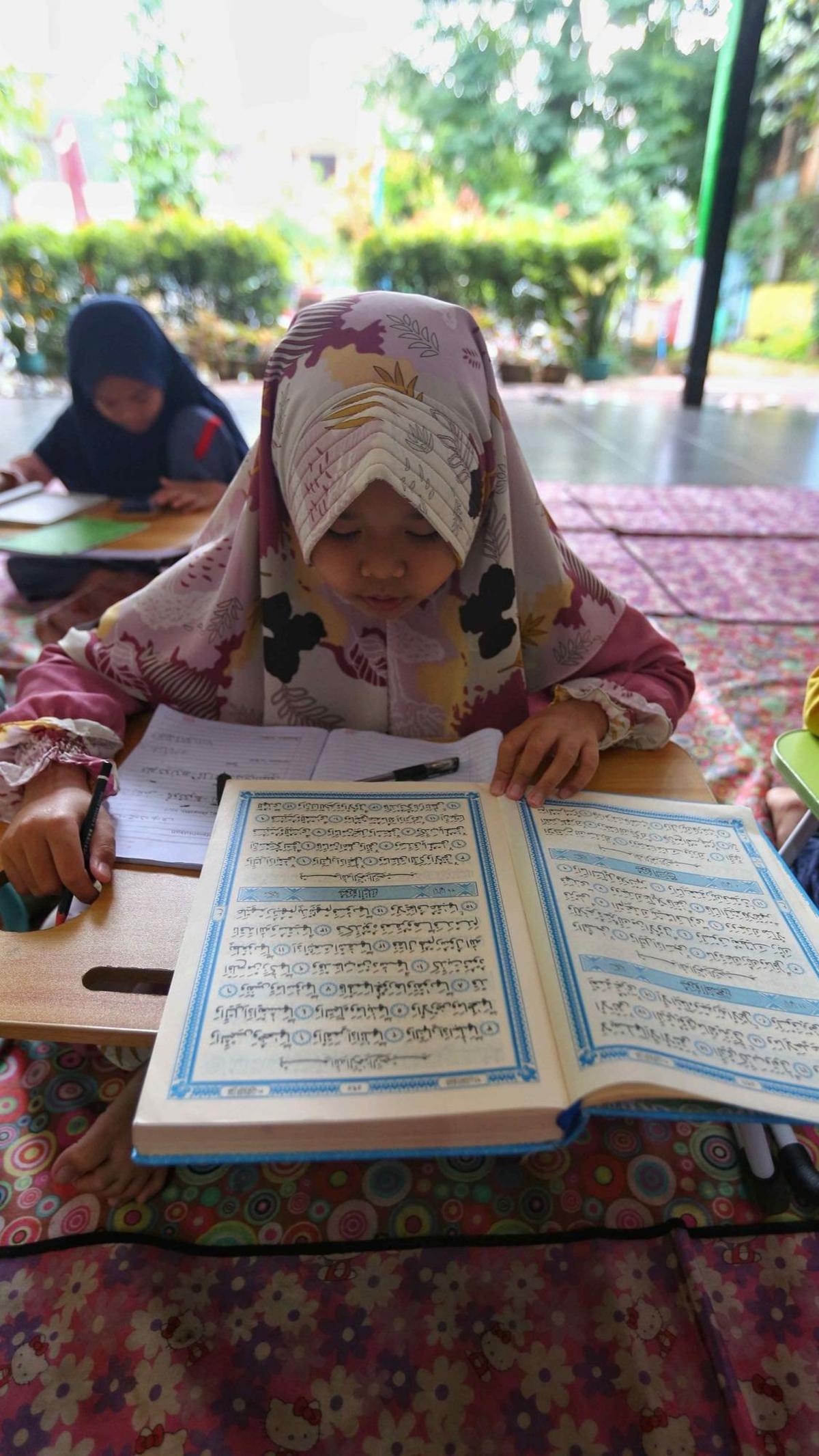 Seorang anak membaca Alquran saat mengikuti pesantren kilat di Ruang Publik Terpadu Ramah Anak (RPTRA) Malinjo. Foto Liputan6.com / Angga Yuniar