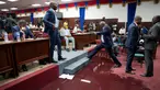 Seorang anggota parlemen melangkahi genangan air hujan pada lantai Gedung Parlemen Haiti di Port-au-Prince, Haiti, Rabu (21/8/2019). Bocornya atap pada Gedung Parlemen Haiti menyebabkan air masuk dan membasahi lantai. (AP Photo/Dieu Nalio Chery)