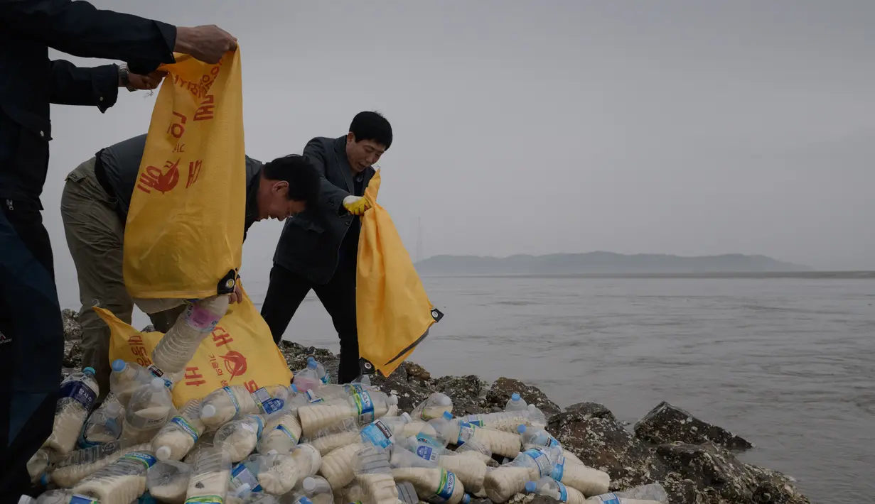 Aktivis pembelot Korea Utara bersiap melemparkan botol-botol ke laut dari pulau Ganghwa di barat Seoul, Selasa (1/5). Botol-botol tersebut berisi di antaranya beras, uang, dan stik memori yang menyimpan informasi terkini tentang dunia. (AFP/ED JONES)