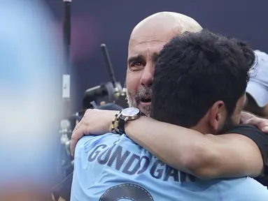 Pelatih Manchester City, Pep Guardiola (kiri) tak dapat menutupi rasa bahagianya sambil memeluk Ilkay Gundongan setelah berhasil membawa Manchester City keluar sebagai juara Piala FA 2022/2023 dalam pertandingan final FA Cup melawan Manchester United yang berlangsung di Wembley, Sabtu (3/6/2023) WIB. (AP Photo/Dave Thompson)