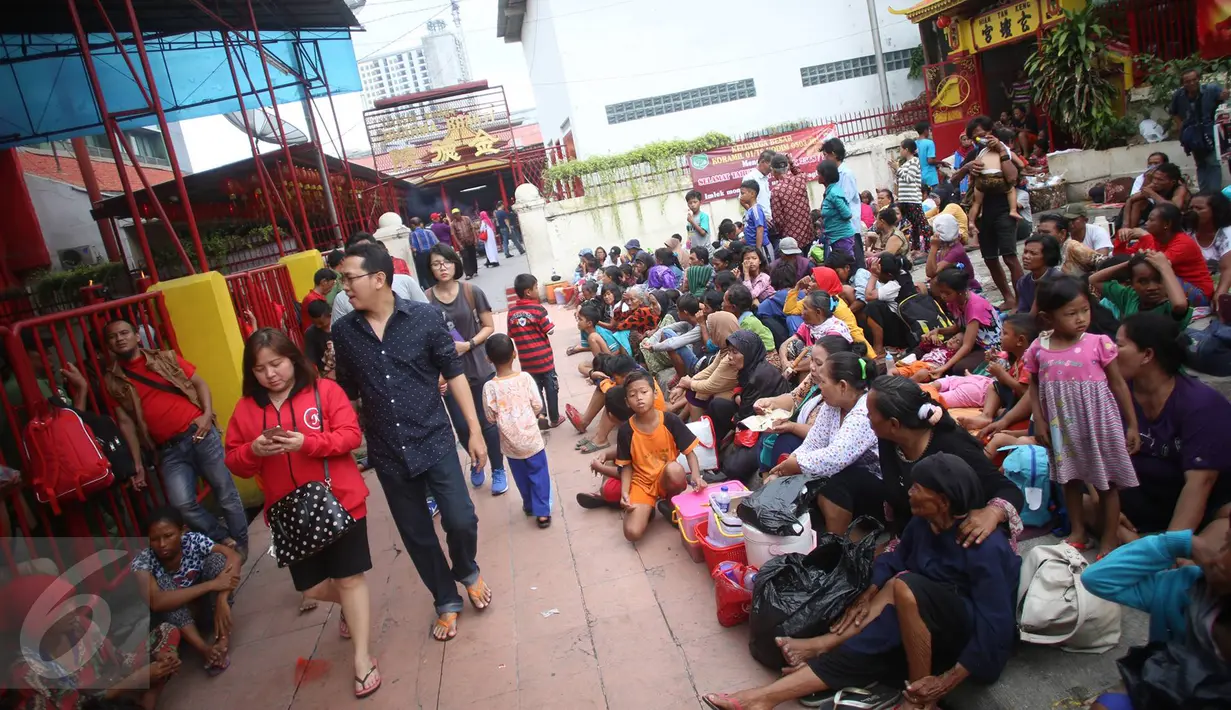 Warga berjalan melintasi pengemis yang menunggu di selasar Vihara Dharma Bahkti, Petak Sembilan, Jakarta Barat, Sabtu (28/1). Rata-rata mereka datang dari luar Jakarta demi mendapatkan angpau yang merupakan sebuah tradisi. (Liputan6.com/Imamnuel Antonius)