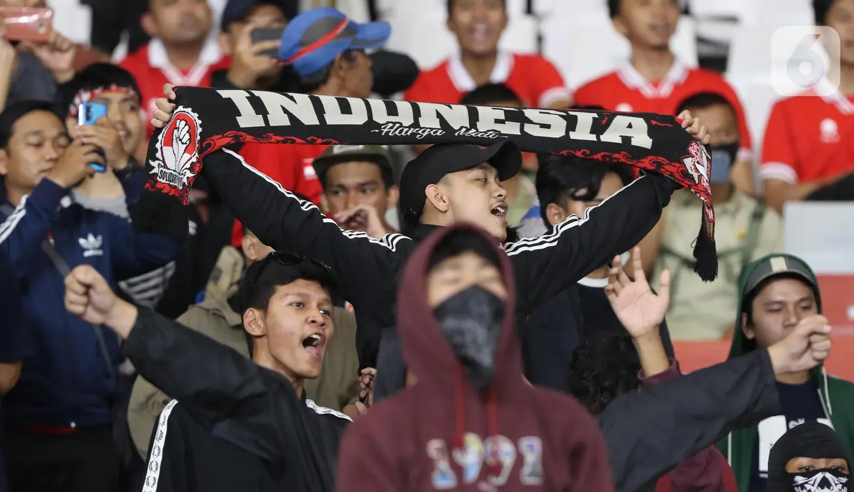 Suporter timnas Indonesia membentang syal dan bernyanyi usai menyaksikan laga timnas Indonesia melawan Thailand pada lanjutan kualifikasi Grup A Piala AFF 2022 di Stadion Utama Gelora Bung Karno, Jakarta, Kamis (29/12/2022). Laga berakhir imbang 1-1. (Liputan6.com/Helmi Fithriansyah)