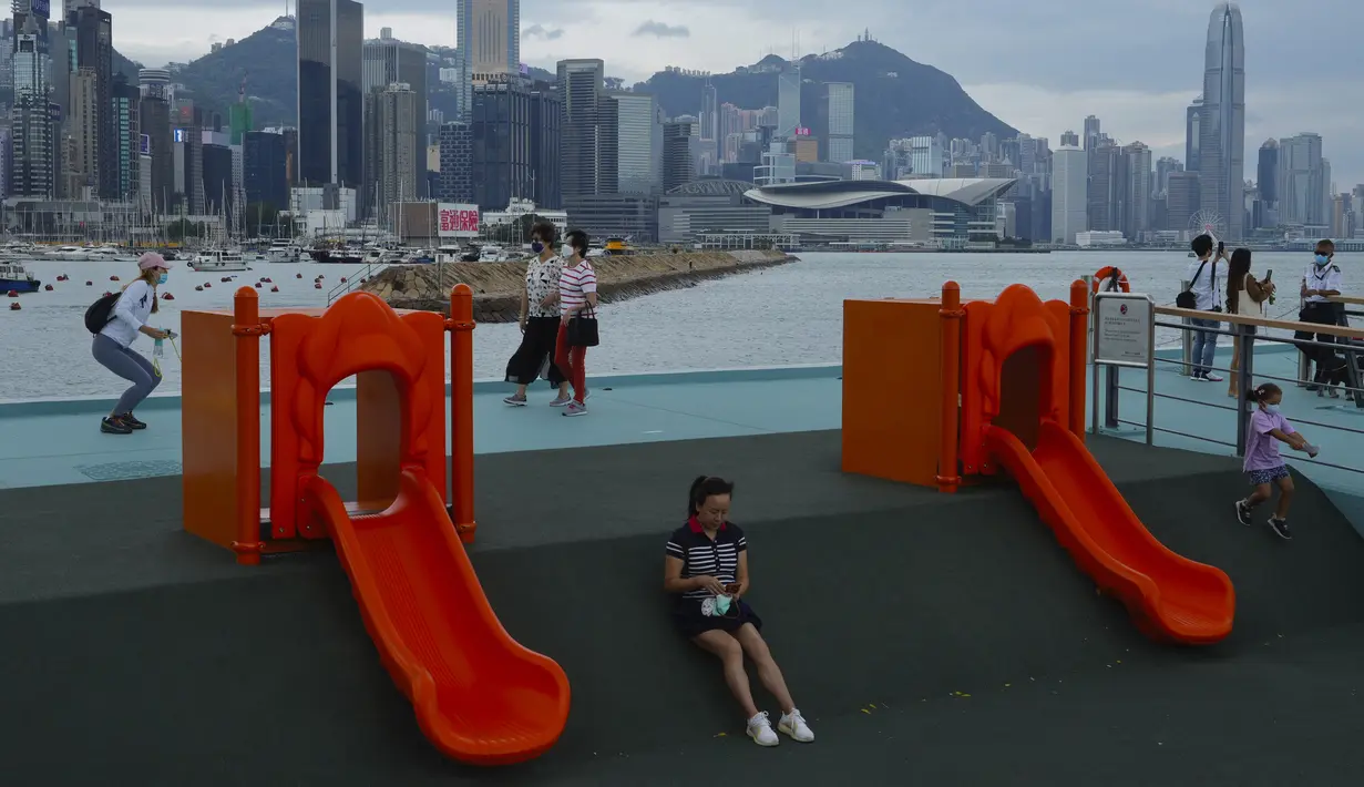 Orang-orang berjalan di taman tepi laut melawan Pelabuhan Victoria saat Badai Tropis Kompasu mendekati Hong Kong, Selasa (12/10/2021). Observatorium Hong Kong mengeluarkan sinyal nomor 8, level tertinggi ketiga dalam skalanya, saat siklon tropis Kompasu semakin mendekati kota. (AP Photo/Vincent Yu)