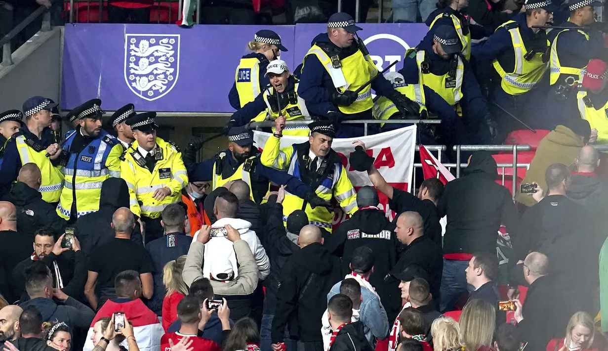 Bentrokan suporter Hungaria dengan polisi saat dimulainya laga Kualifikasi Piala Dunia 2022 melawan Inggris di Stadion Wembley, Rabu (13/10/2021) dini hari WIB. Bentrokan terjadi saat polisi berusaha menangkap penonton yang melakukan pelecehan rasial terhadap petugas stadion. (Nick Potts/PA via AP)