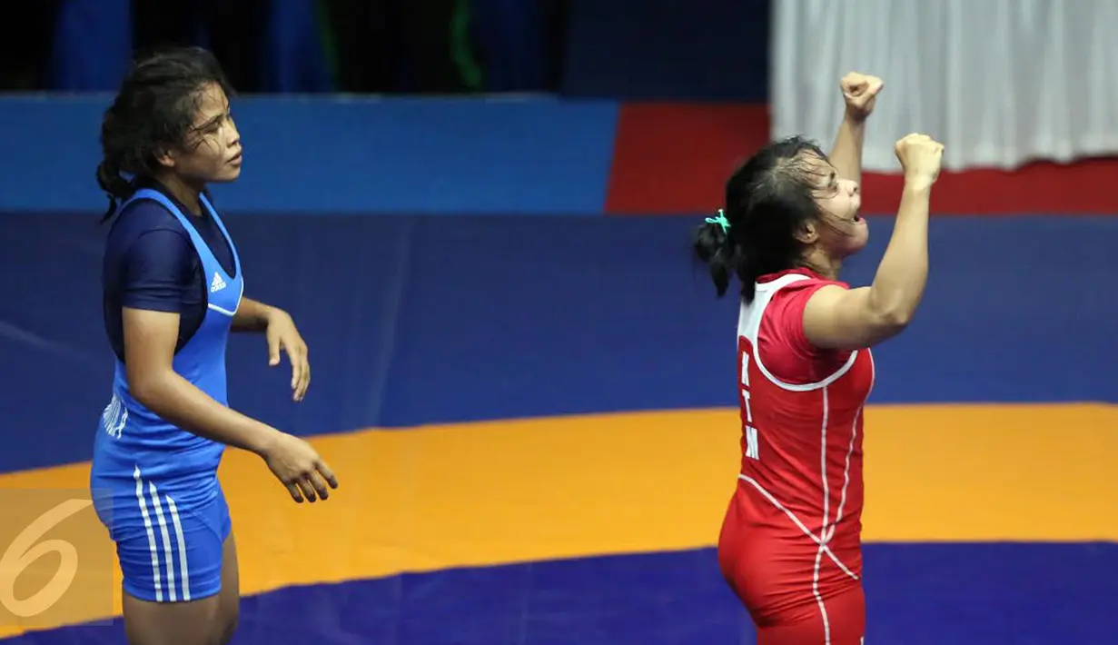 Pegulat putri Kaltim, Inadrah (kostum merah) mengangkat tangan usai memastikan menang melawan pegulat Sumbar Mardiatul di final gaya bebas kelas 53 kg putri pada PON XIX di Arena Saparua Sport Park, Bandung, Sabtu (24/9). (Liputan6.com/Helmi Fithriansyah)