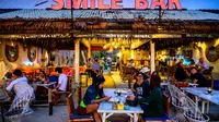 Orang-orang duduk di sebuah bar , saat para turis memanfaatkan program "Kotak Pasir Phuket" untuk pengunjung yang divaksinasi penuh terhadap virus corona Covid-19 di pulau Phuket Thailand (25/10/2021). (AFP/Mladen Antonov)