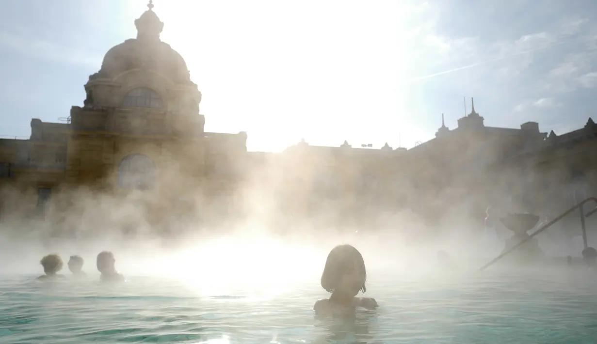 Orang-orang menikmati air hangat di kolam relaksasi Szechenyi, di Budapest, Hongaria pada 15 Februari 2019. Szechenyi Thermal Bath adalah salah satu lokasi pemandian umum tertua dan terbesar di Budapest. (VALERY HACHE / AFP)