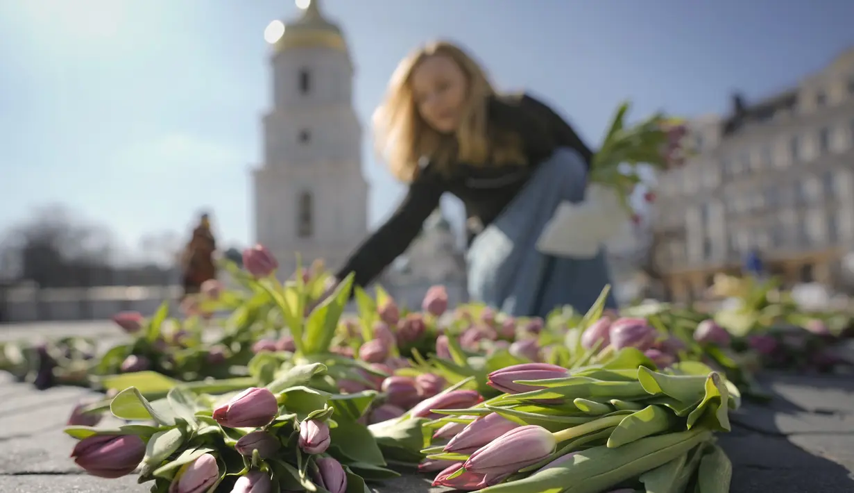 Seorang wanita menata bunga tulip di alun-alun Sophia di Kiev, Ukraina (18/3/2022). Warga Kiev turun ke alun-alun pusat untuk menata sekitar 1,5 juta bunga tulip bentuk lambang negara dalam pertunjukan normal yang menantang saat pasukan Rusia mengepung dan mengebom kota. (AP Photo/Vadim Ghirda)
