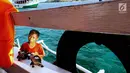 Kevin saat menawarkan kerajinan khas Pulau Komodo di atas kapal semi pinisi di Pink Beach, Taman Nasional Komodo, Sabtu, (9/10). Makanan kecil dan minuman di atas kapal dibawanya dari rumah. (Liputan6.com/Fery Pradolo)