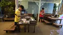 Pelanggan Chaopraya Antique Café di tepi sungai menikmati ketinggian air di Sungai Chao Phraya dekat Bangkok, Thailand, Kamis (7/10/2021). Restoran yang dilanda banjir ini menjadi tempat makan tidak biasa di mana pengunjung menikmati santapan makanan dengan kaki terendam. (AP Photo/Sakchai Lalit)