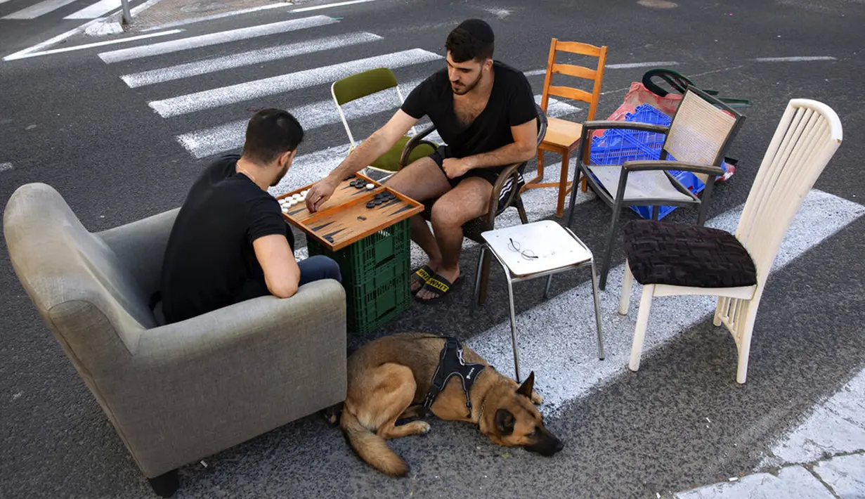 Warga bermain backgammon di jalan bebas mobil saat Hari Raya Yom Kippur di Ramat Gan, Israel, Kamis (16/9/2021). Yom Kippur atau Hari Penebusan Dosa merupakan hari raya paling suci umat Yahudi dimana mereka akan berhenti beraktivitas secara total. (AP Photo/Oded Balilty)
