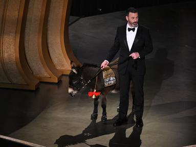 Pembawa acara Oscar 2023, Jimmy Kimmel berjalan di atas panggung dengan keledai selama ajang Academy Awards ke-95 di Dolby Theatre di Los Angeles, California, Minggu (12/3/2023). Jimmy Kimmel tiba-tiba membawa seekor keledai ke atas panggung seusai cuplikan film The Banshees of Inisherin yang masuk nominasi best picture. (Photo by Patrick T. Fallon / AFP)