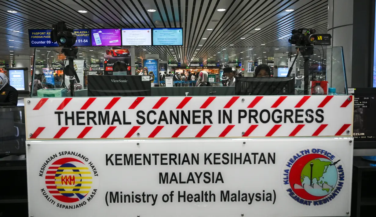 Petugas kesehatan memantau suhu tubuh penumpang yang tiba dengan 'thermal scanner' di Bandara Internasional Kuala Lumpur, Sepang, pada Selasa (21/1/2020). Pemerintah Malaysia mulai mengoperasikan alat pemindai suhu tubuh merespons penyebaran virus korona yang kian masif di China. (MOHD RASFAN/AFP)