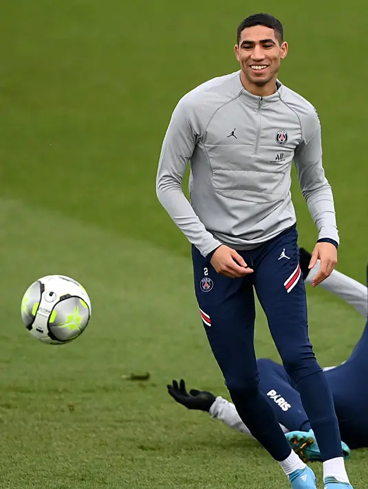Bek PSG Achraf Hakimi menatap bola selama sesi latihan di tempat latihan klub sepak bola Camp des Loges Paris Saint-Germain, di Saint-Germain-en-Laye, barat Paris pada 10 Februari 2022. PSG akan menjamu Rennes pada lanjutan Ligue 1, Sabtu 12 Februari 2022 dini hari WIB. (FRANCK FIFE / AFP)