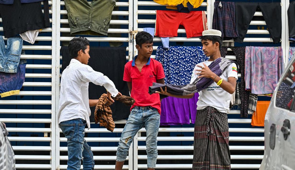 Pengungsi Rohingya menggantung cucian di area parkir gedung pemerintah setelah penduduk desa menolak kamp relokasi mereka di Banda Aceh, Rabu (13/12/2023). Sebanyak 137 pengungsi Rohingya yang ditolak warga, ditampung sementara di gedung serbaguna milik Pemerintah Aceh. (CHAIDEER MAHYUDDIN/AFP)