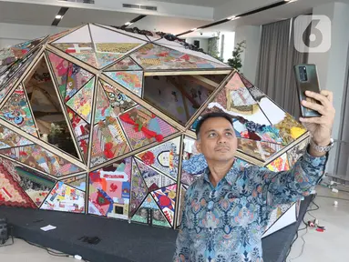 Pengunjung berswafoto dengan karya seni kolektif bertajuk Hati Polyhedron: Simbol Persatuan dalam Keberagaman (The Hati Polyhedron Project: A Symbol of Unity in Diversity) yang diinisiasi oleh Scholas Occurrentes di Kompleks gereja Katedral, Jakarta, Senin (2/9/2024). (merdeka.com / Arie Basuki)